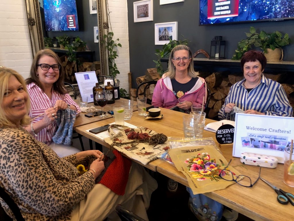Four women crafting together at a table